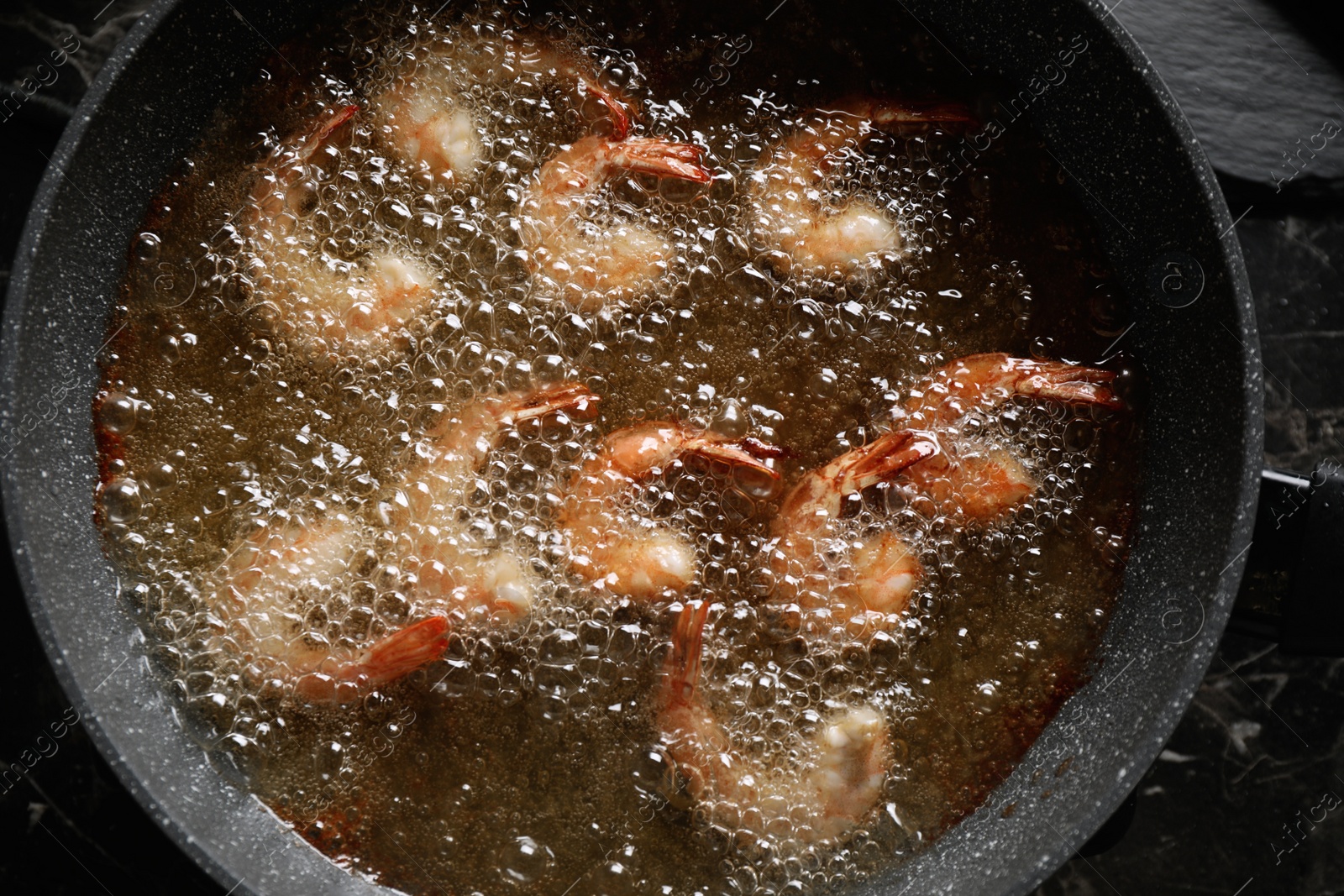 Photo of Cooking delicious shrimps in hot oil, top view