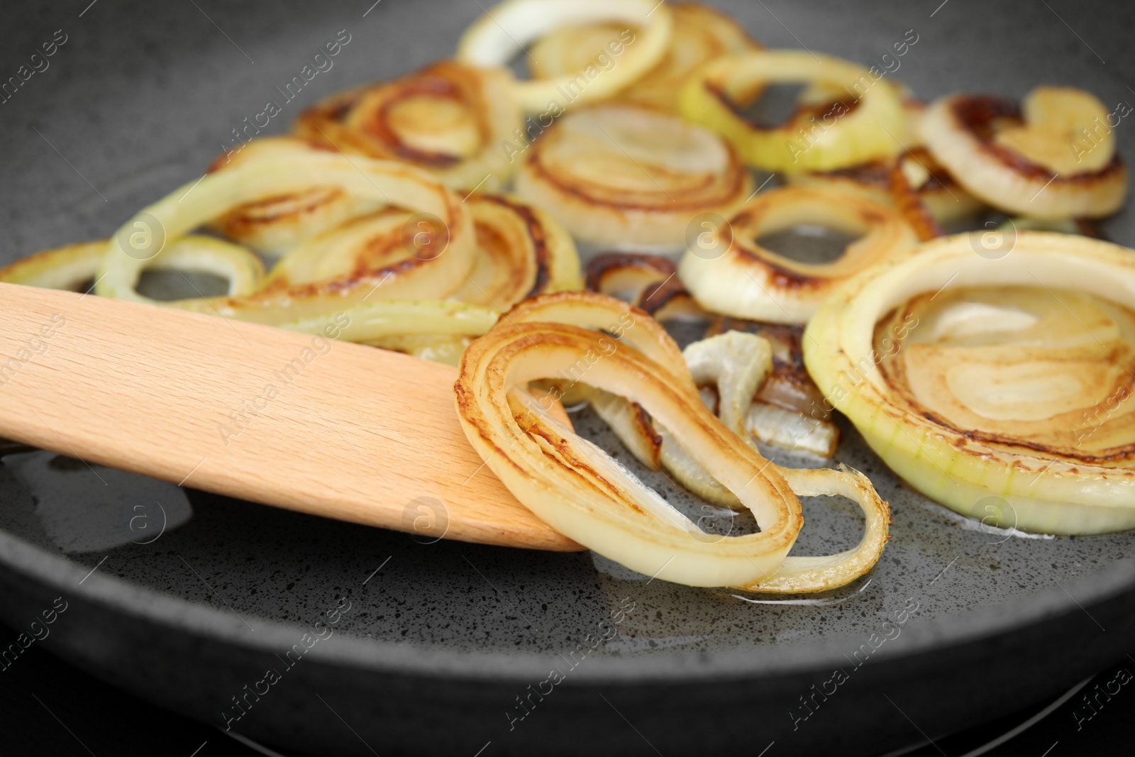 Photo of Cooking onion rings in frying pan, closeup