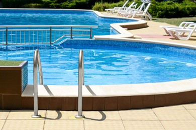 Photo of Swimming pool with deck chairs at resort on sunny day