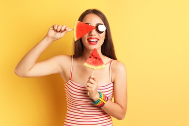 Beautiful young woman posing with watermelon on color background