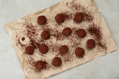 Photo of Delicious chocolate candies powdered with cocoa on light table, flat lay