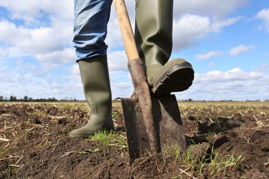 Man digging soil with shovel in field, closeup