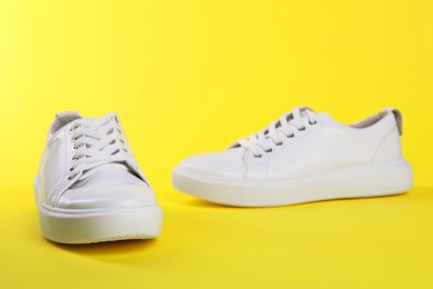 Photo of Pair of stylish white sneakers on yellow background