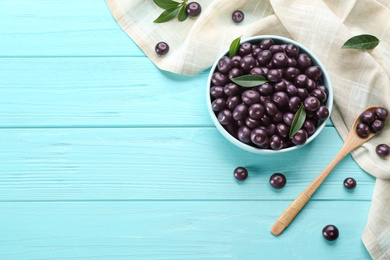 Flat lay composition with tasty acai berries on light blue wooden table. Space for text