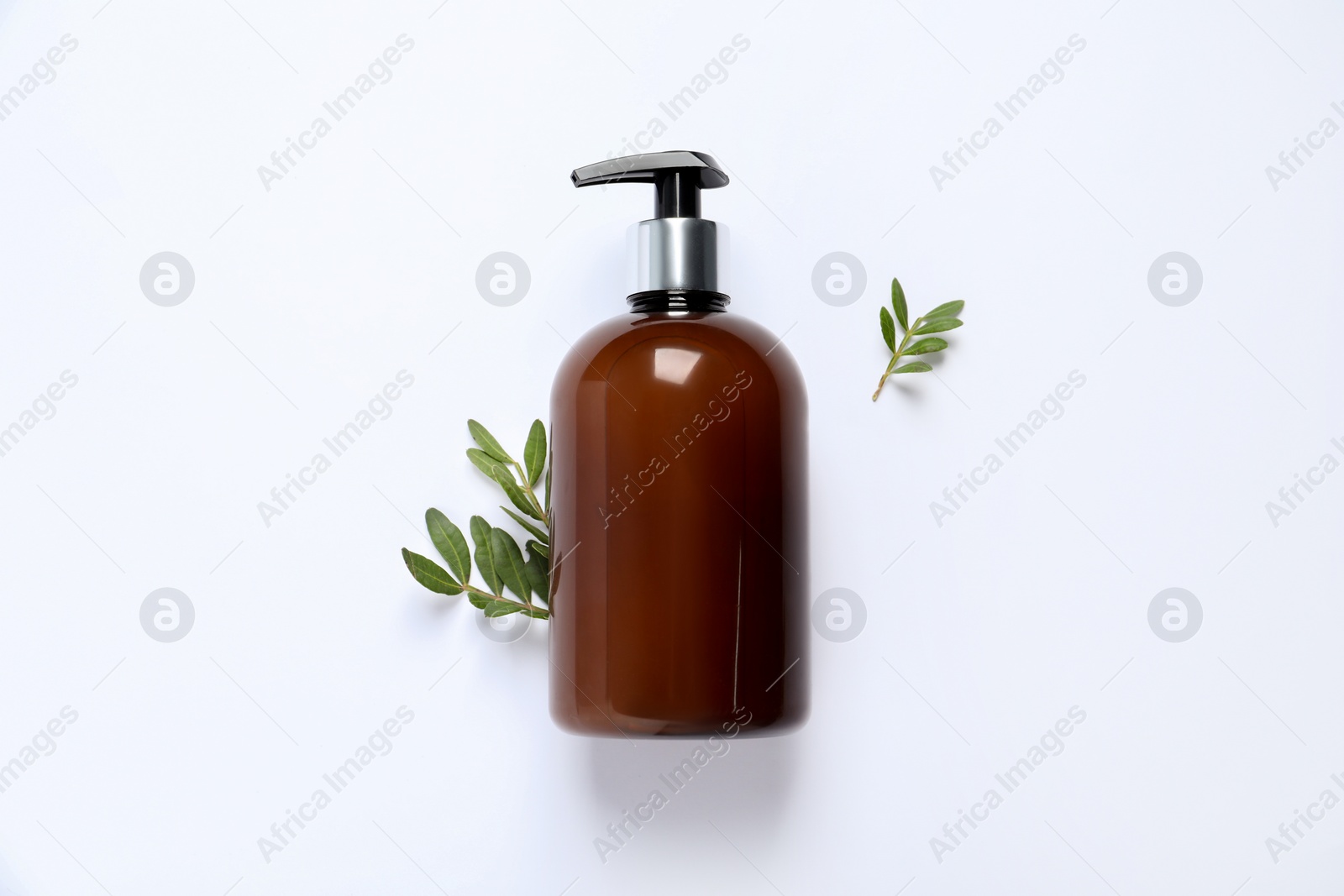 Photo of Bottle of cosmetic product and green leaves on white background, flat lay