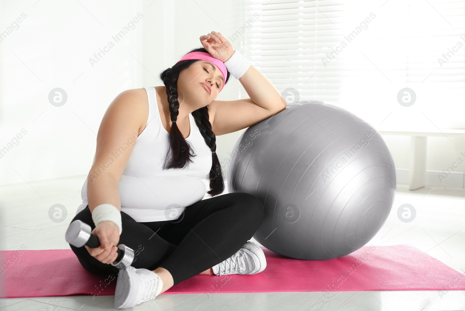 Photo of Lazy overweight woman with fit ball and dumbbell at gym