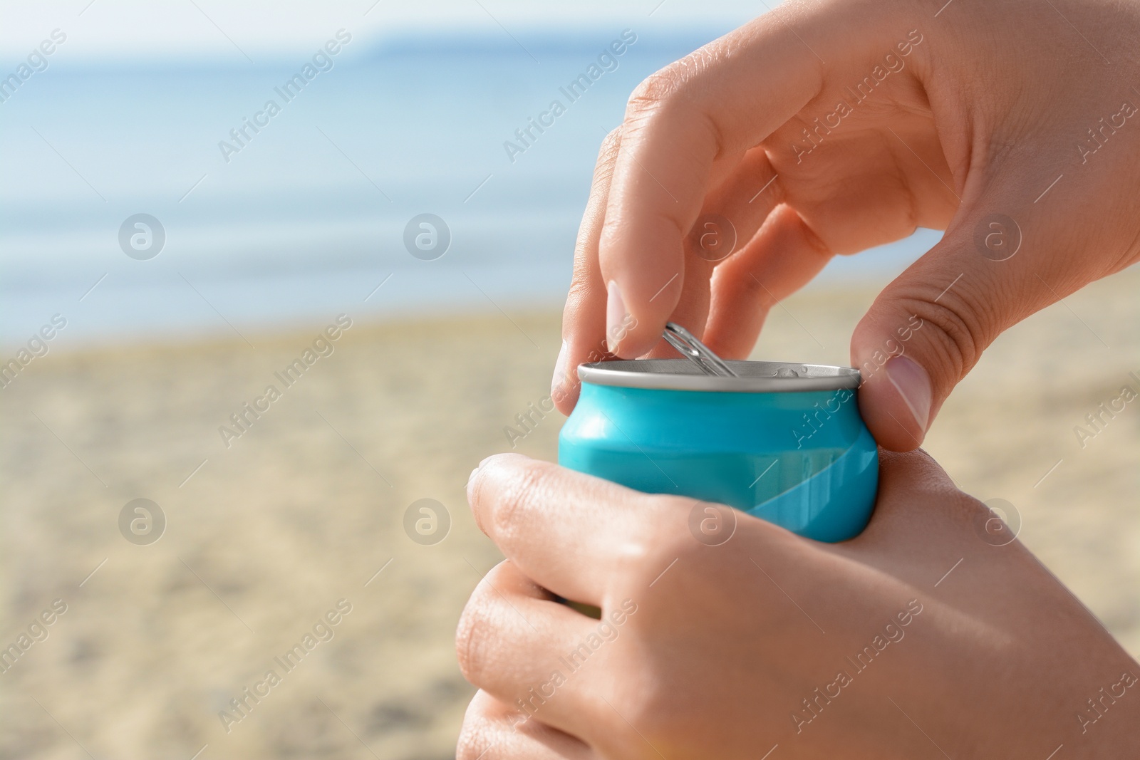 Photo of Woman opening aluminum can with beverage on beach, closeup. Space for text