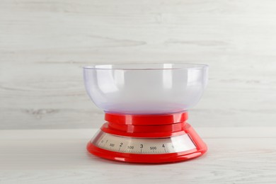 Photo of Kitchen scale with plastic bowl on white wooden table