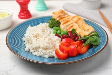 Photo of Plate of boiled rice with vegetables and meat on table