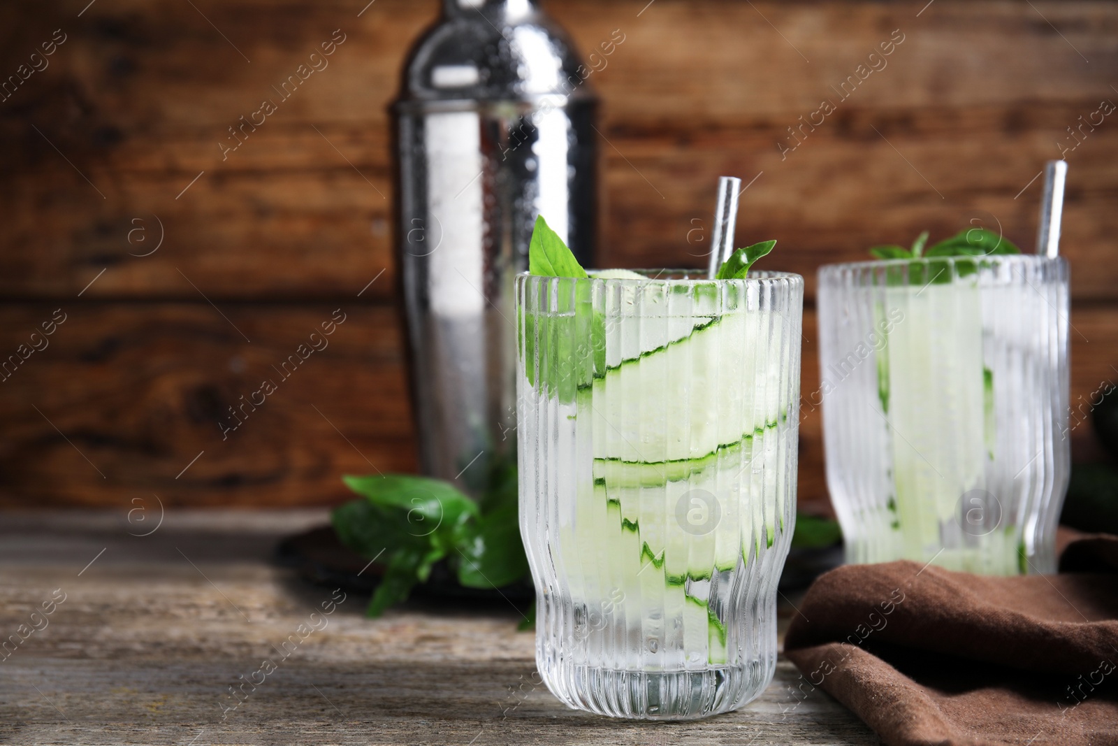 Photo of Glasses of refreshing cucumber water with basil on wooden table, space for text