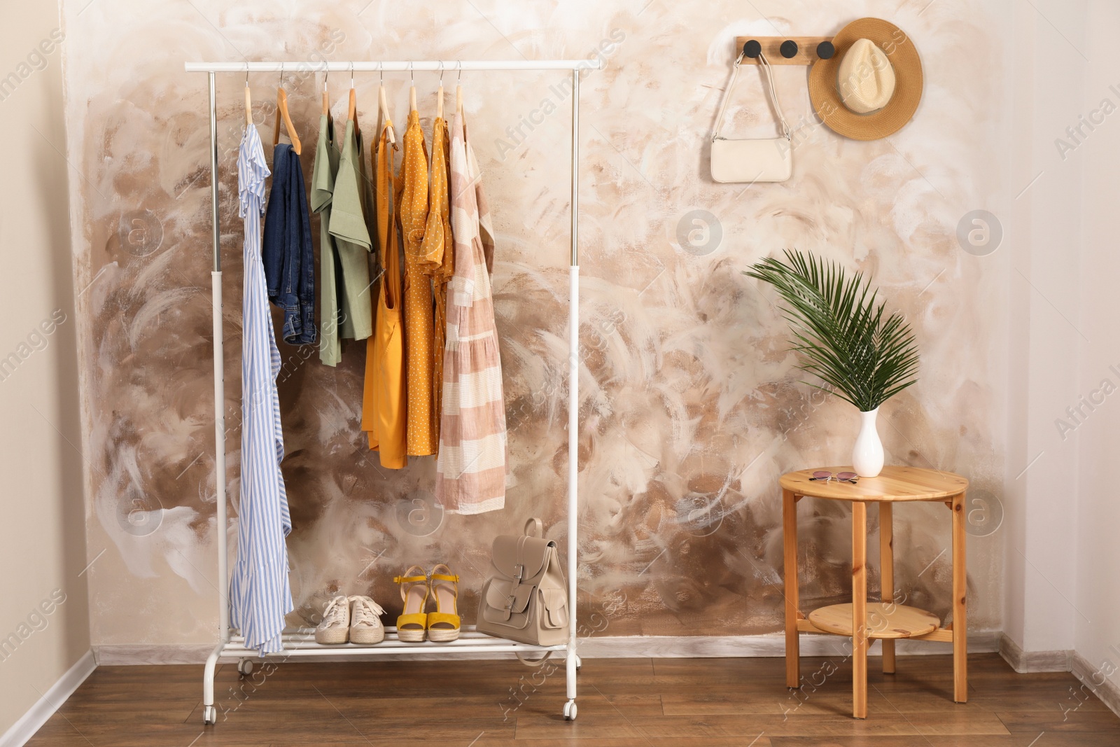 Photo of Different stylish clothes hanging on rack in room