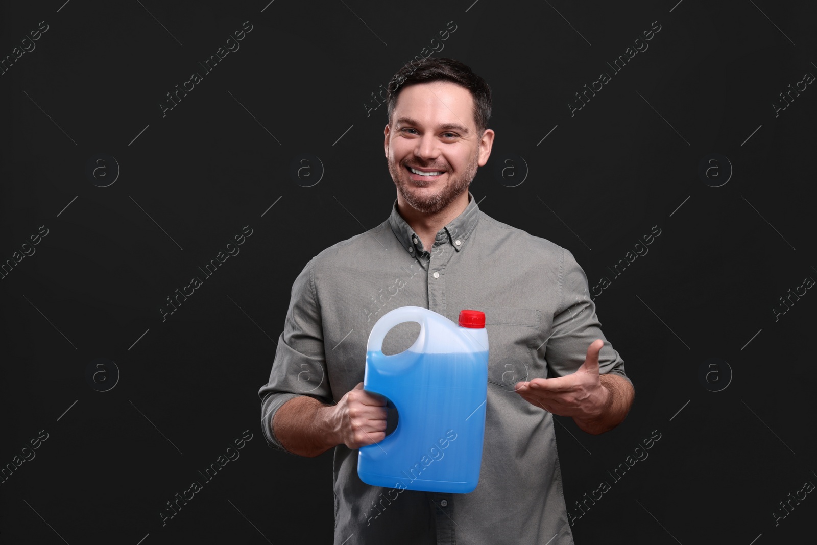 Photo of Man showing canister with blue liquid on black background