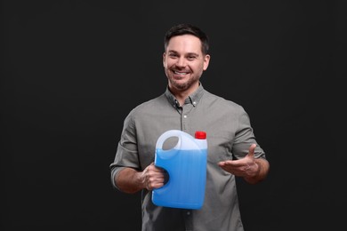 Photo of Man showing canister with blue liquid on black background