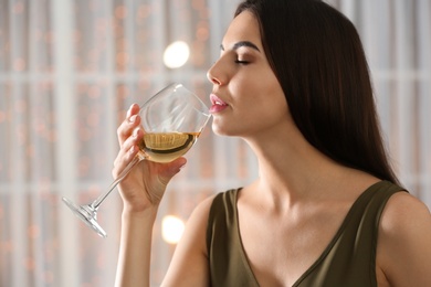 Photo of Beautiful young woman with glass of luxury white wine indoors