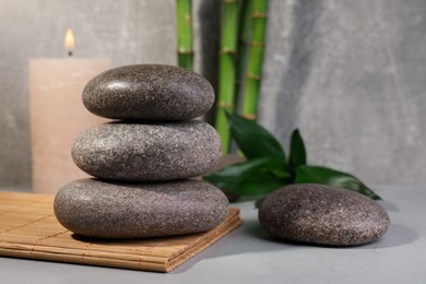 Photo of Spa stones, bamboo and candle on light grey table, space for text
