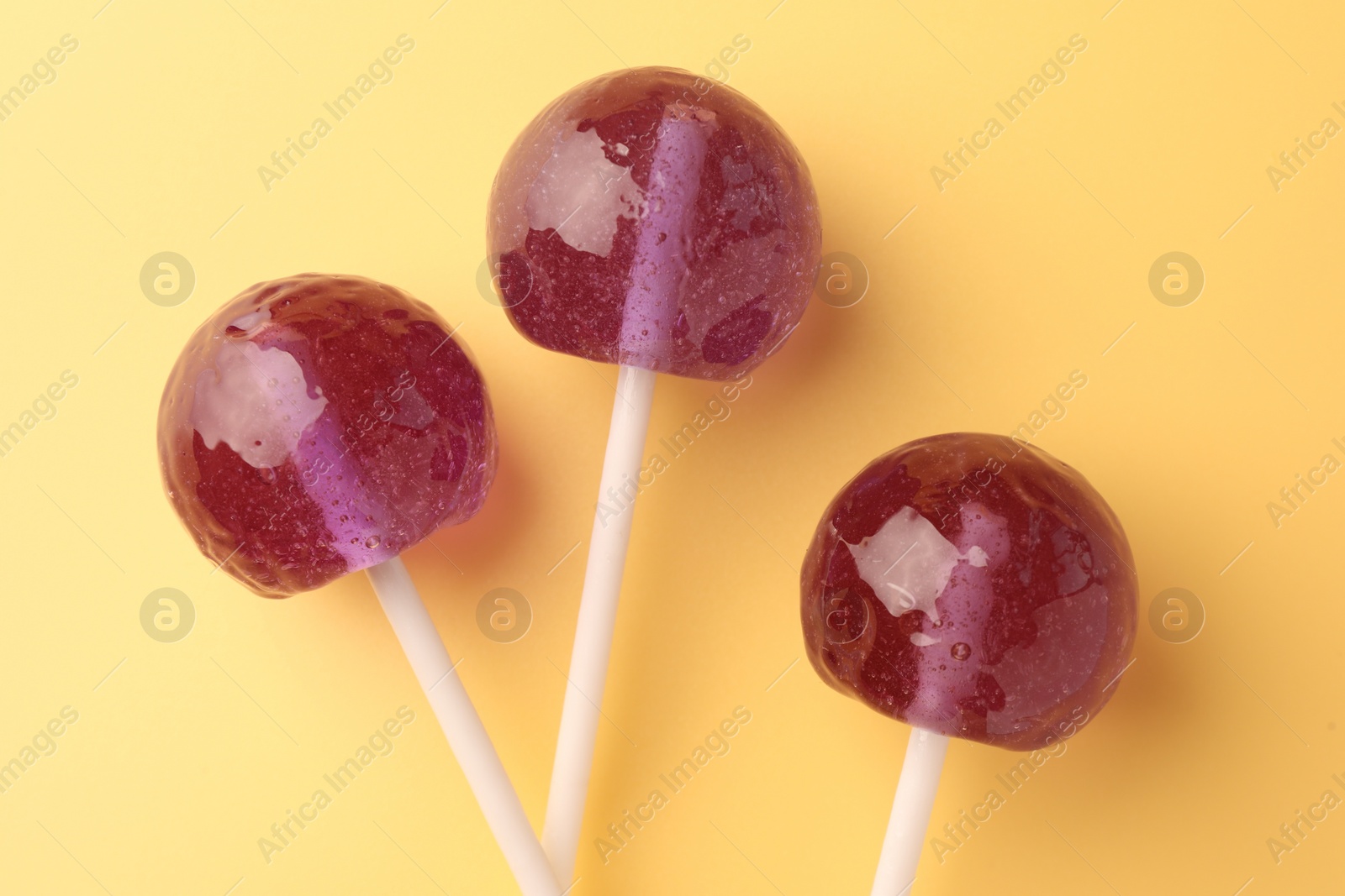 Photo of Tasty lollipops on yellow background, flat lay