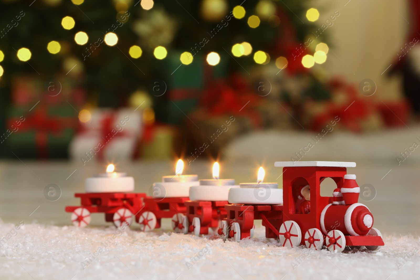 Photo of Toy train with burning candles near Christmas tree in room, closeup. Space for text