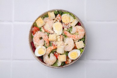 Photo of Delicious Caesar salad with shrimps on white tiled table, top view