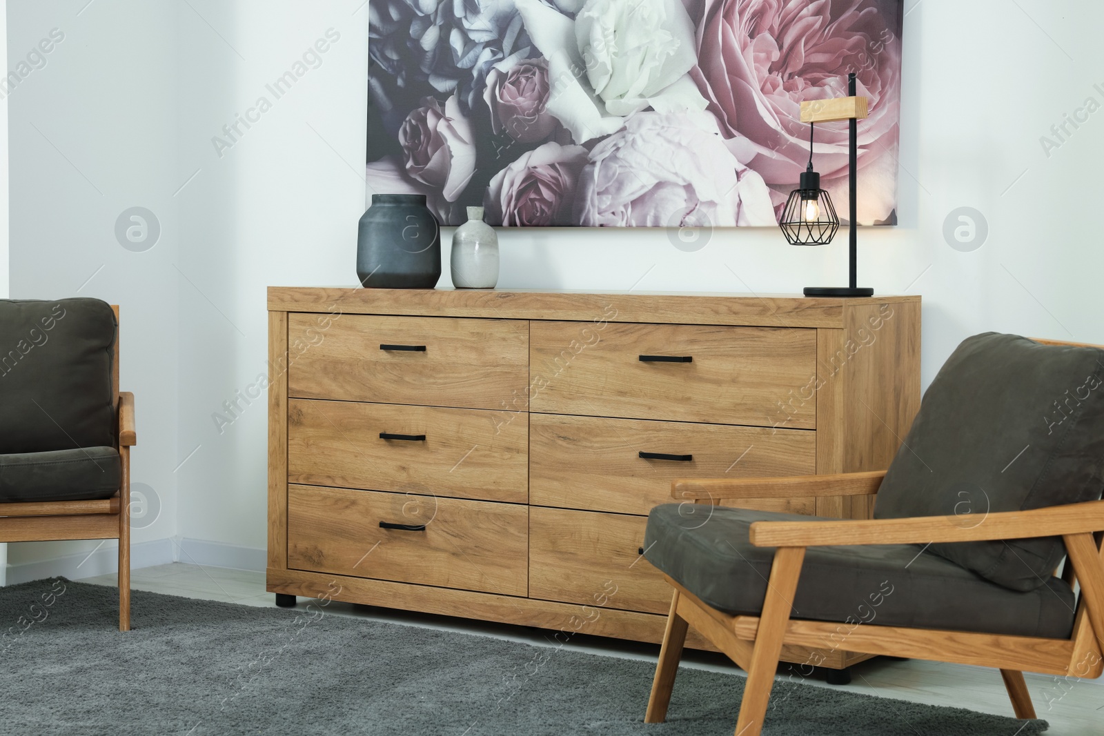 Photo of Stylish living room with wooden chest of drawers, armchairs and beautiful picture. Interior design