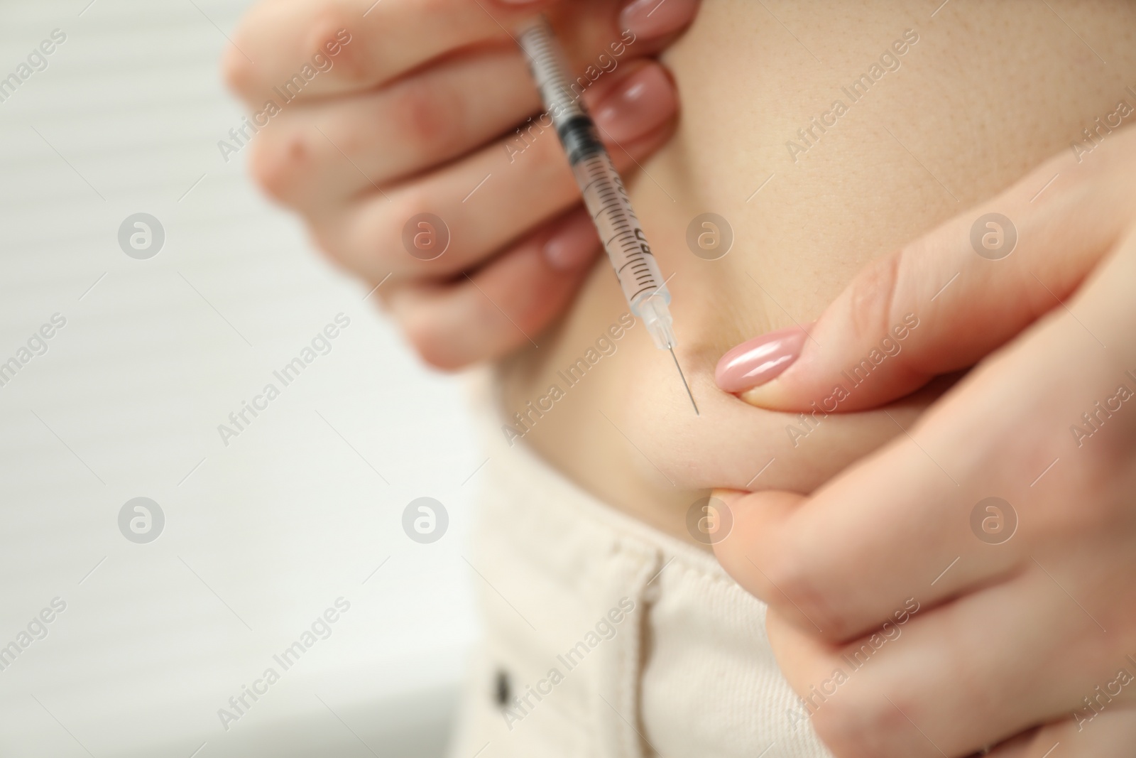 Photo of Diabetes. Woman making insulin injection into her belly indoors, closeup