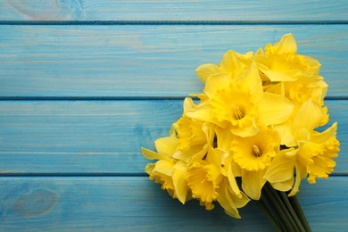 Beautiful daffodil bouquet on blue wooden table, top view. Space for text