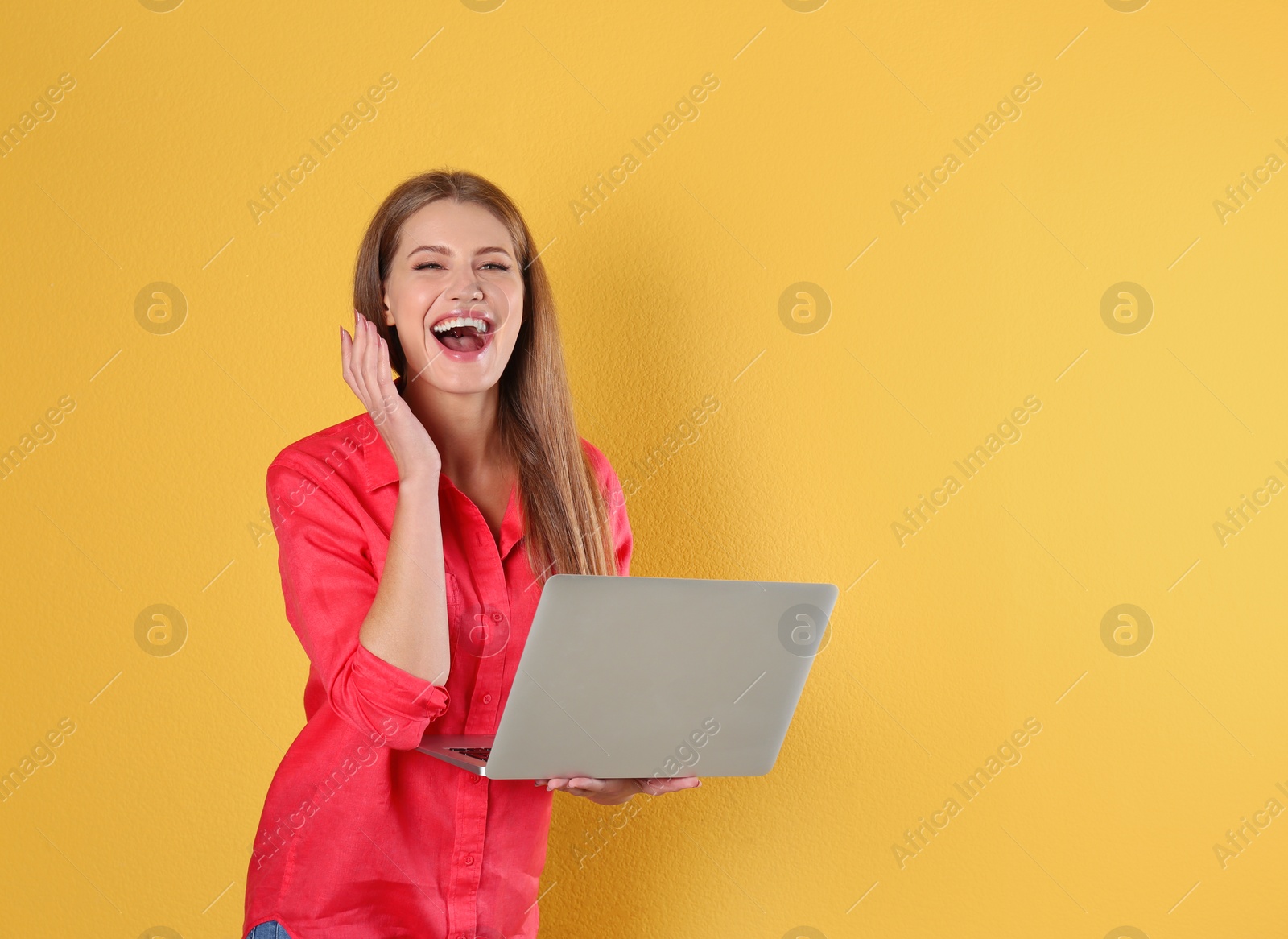 Photo of Emotional young woman with laptop celebrating victory on color background. Space for text