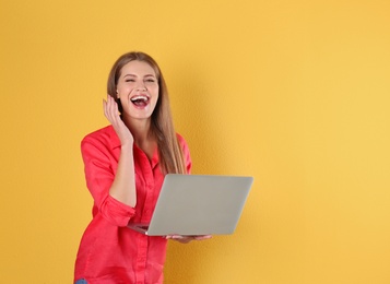 Photo of Emotional young woman with laptop celebrating victory on color background. Space for text