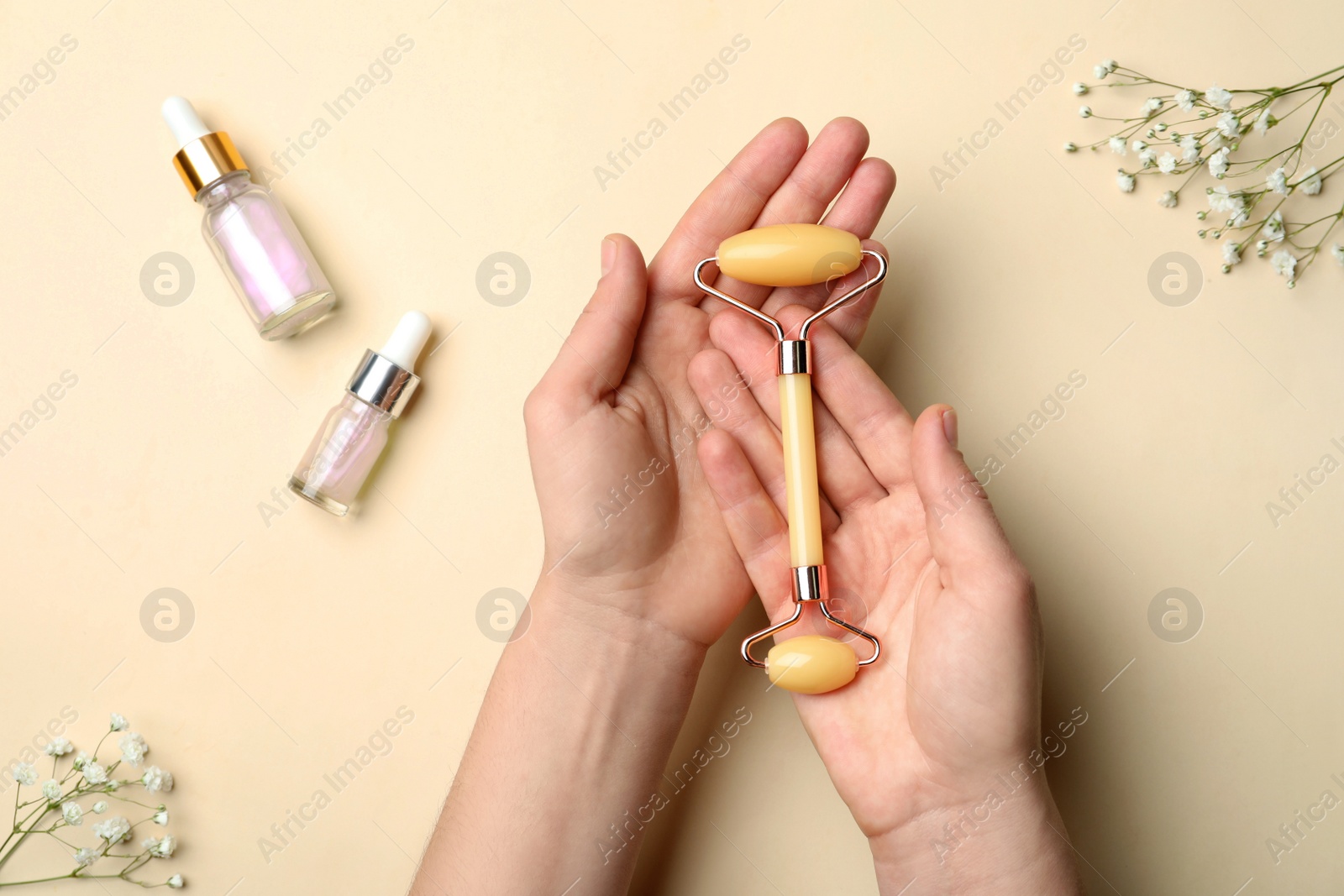 Photo of Woman with natural face roller on beige background, top view