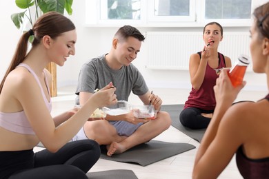 Photo of Group of people eating healthy food after yoga class indoors