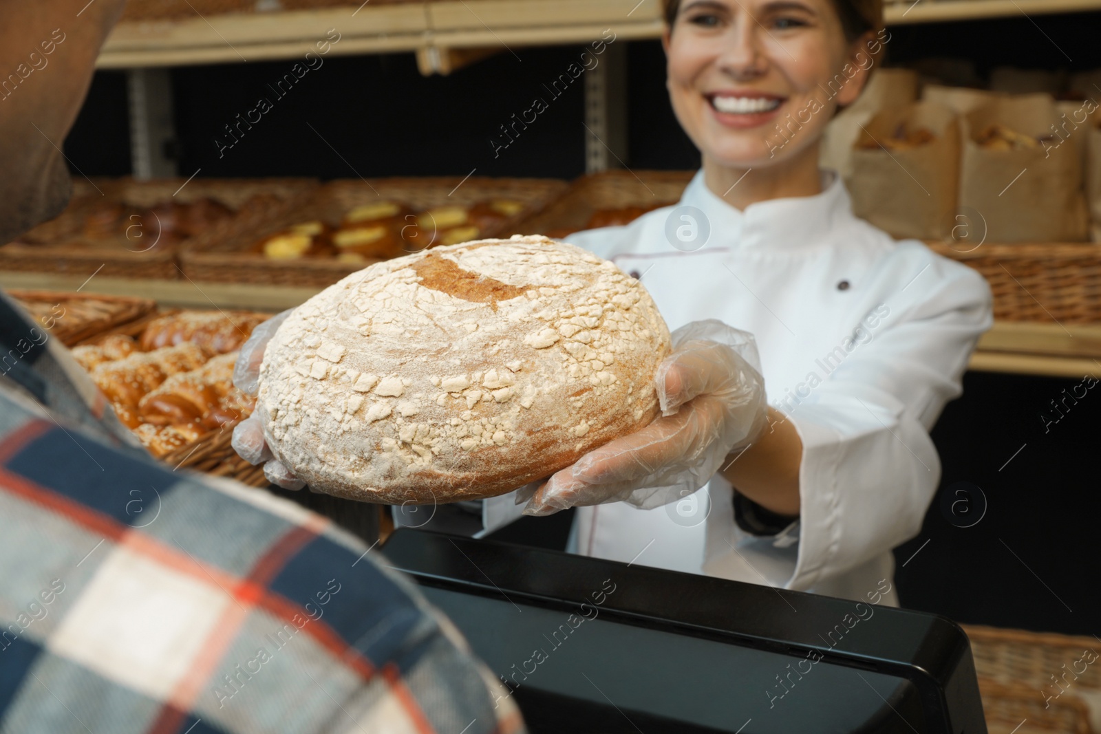 Photo of Baker giving customer fresh bread in store, closeup