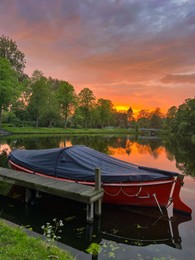 Photo of Scenic view of pond with moored boat at sunset