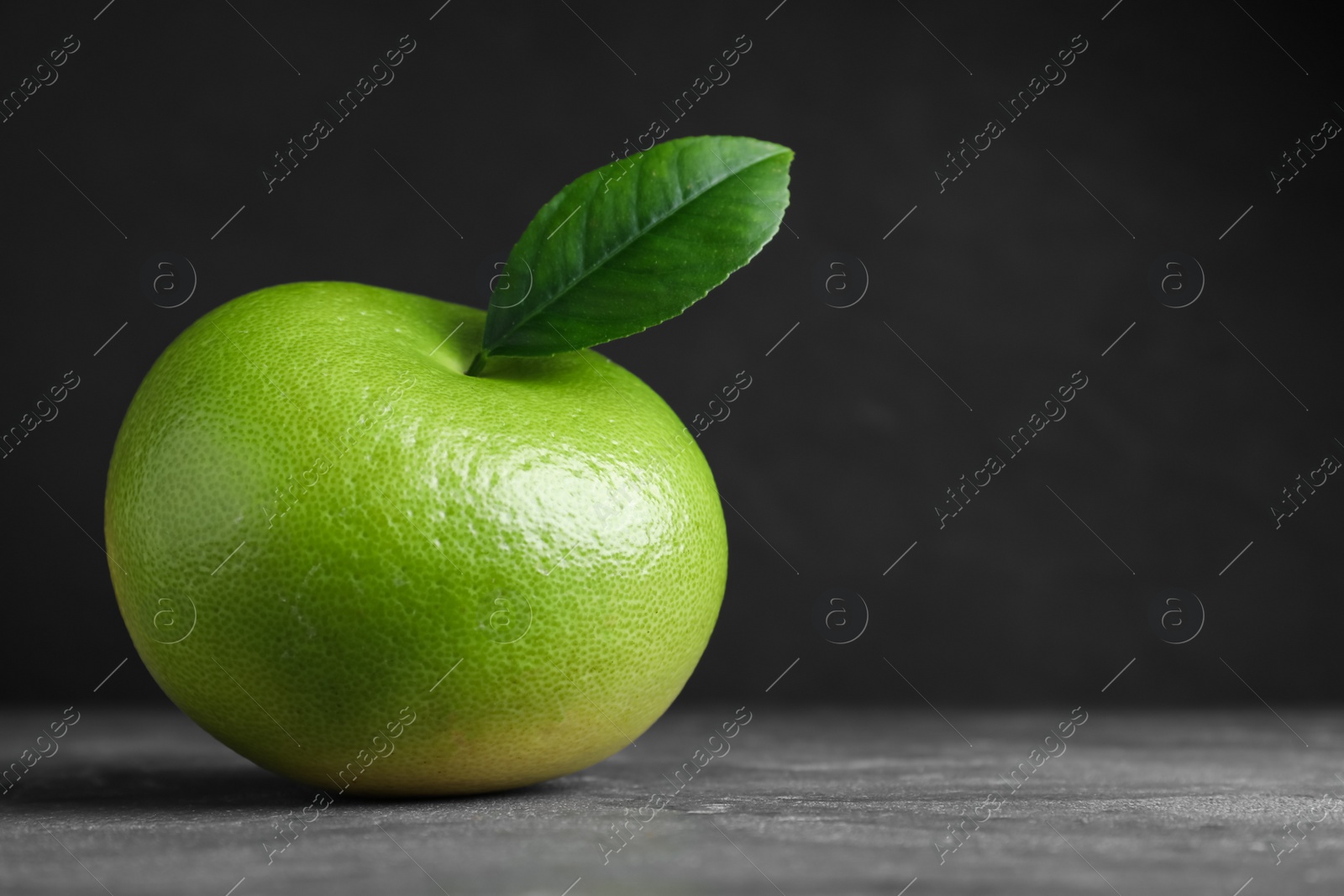 Photo of Fresh ripe sweetie with green leaf on grey table, space for text