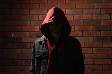Thief in hoodie against red brick wall