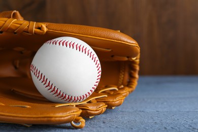 Photo of Leather baseball glove with ball on grey wooden table, closeup. Space for text