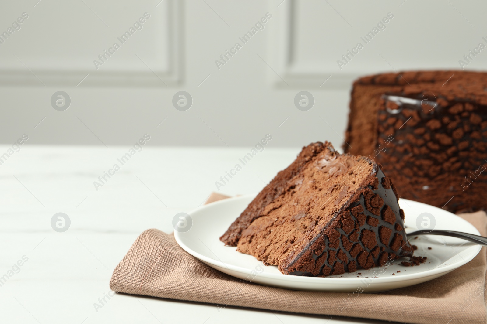 Photo of Piece of delicious chocolate truffle cake on white table, space for text