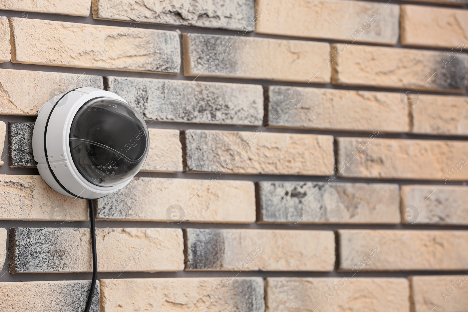 Photo of Modern security CCTV camera on brick wall