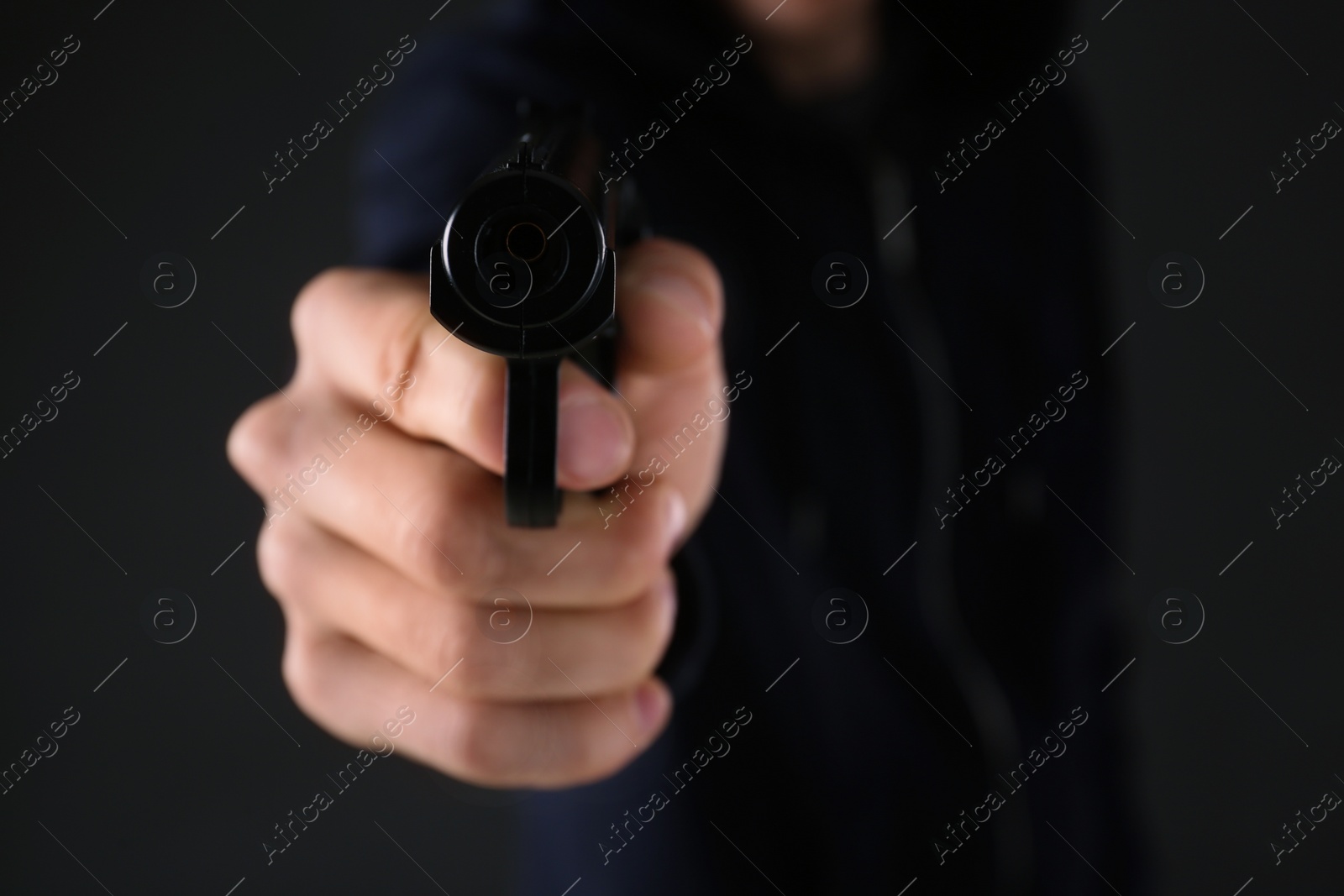 Photo of Man aiming gun on dark background, closeup