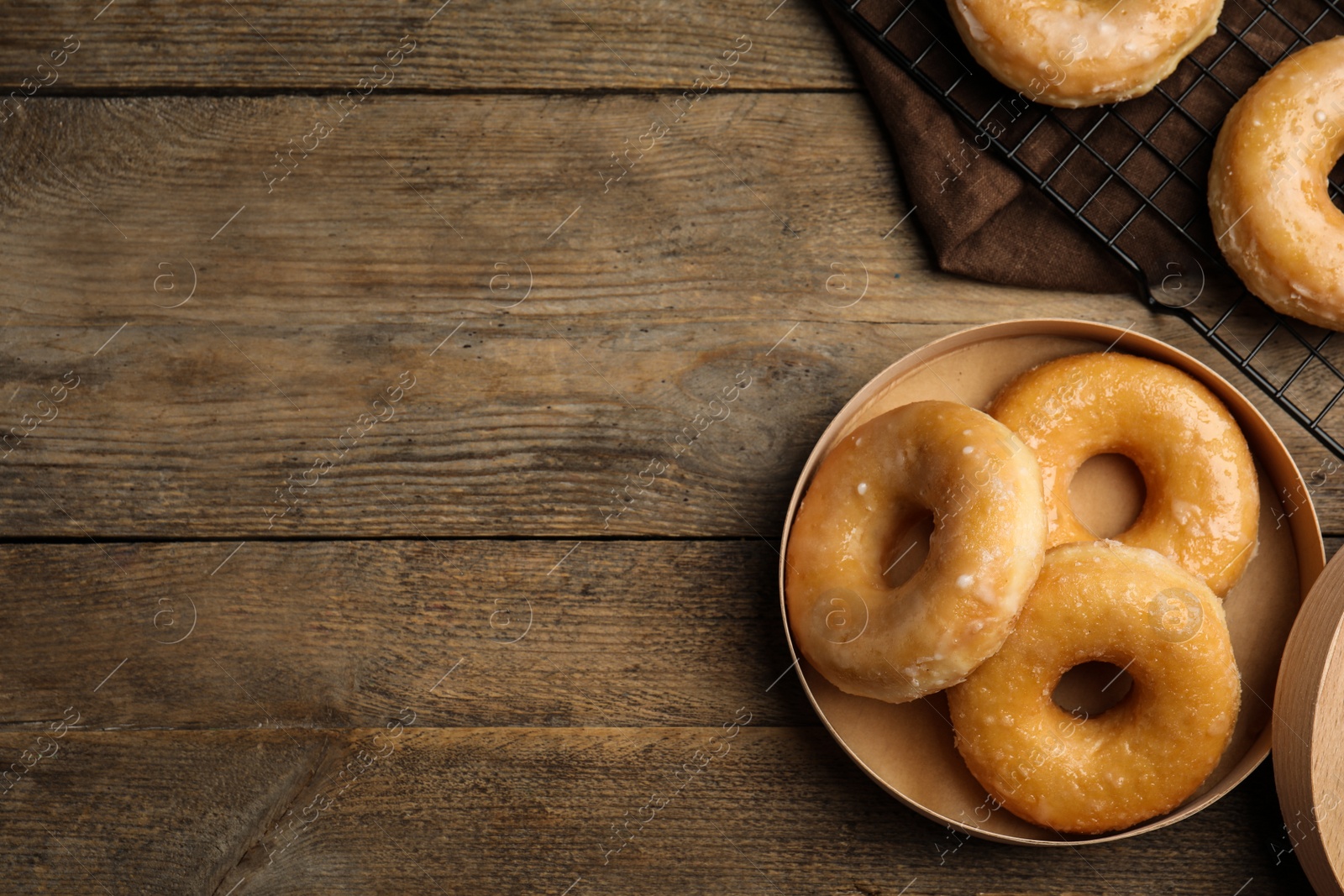 Photo of Delicious donuts in box on wooden table, flat lay. Space for text