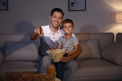 Family watching TV with popcorn in room at evening time