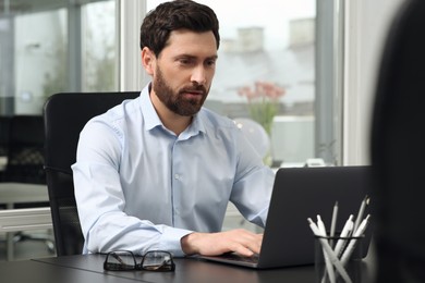 Man working on laptop at black desk in office