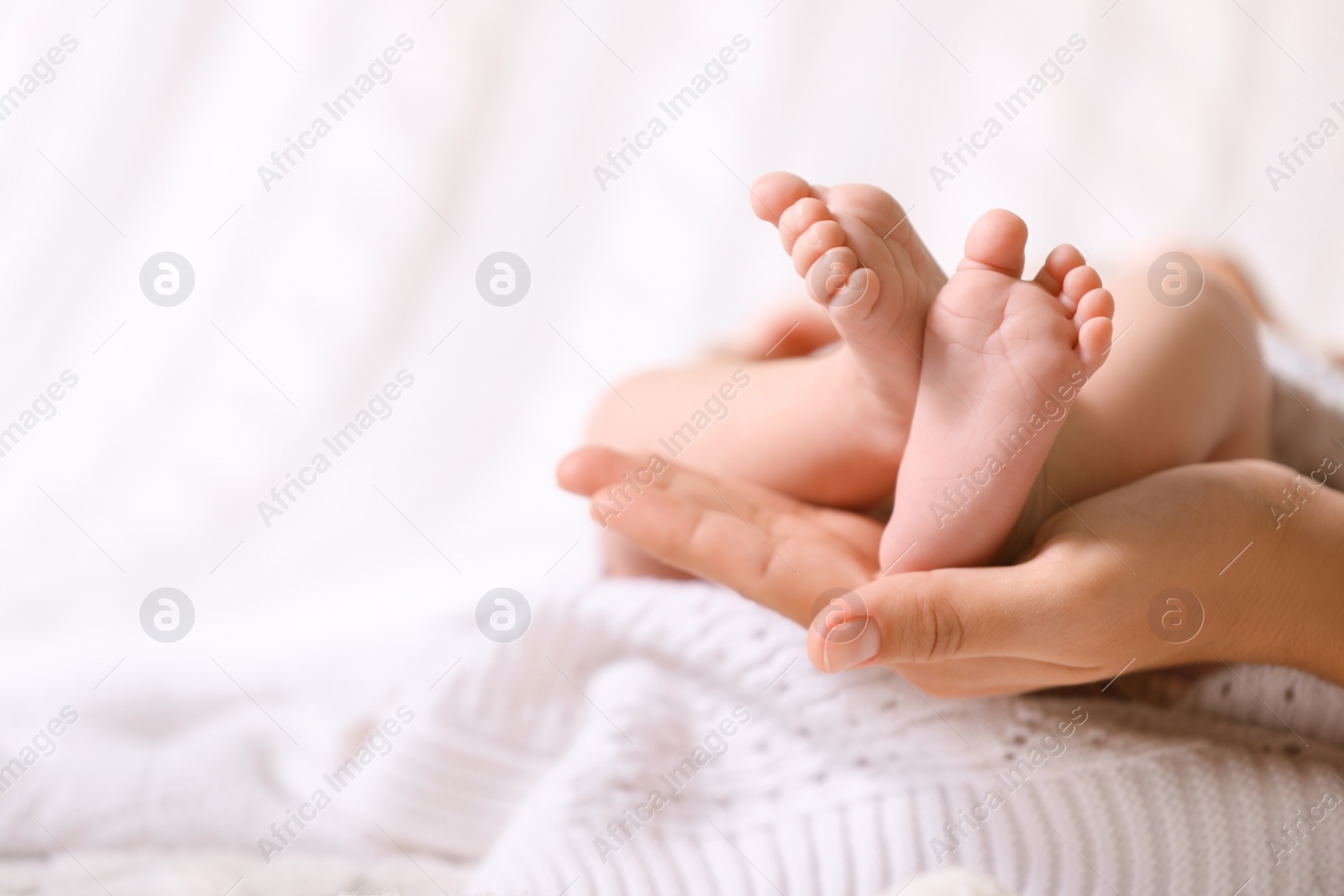 Photo of Mother and her newborn baby on white knitted plaid, closeup. Space for text