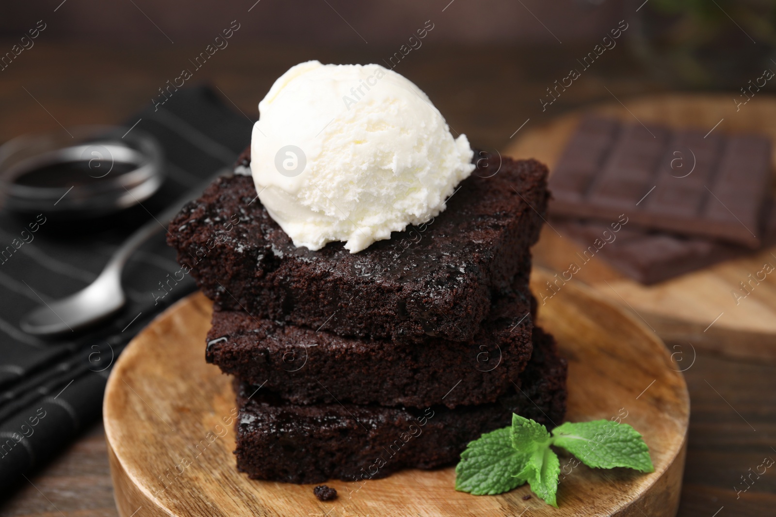 Photo of Tasty brownies served with ice cream on wooden table, closeup