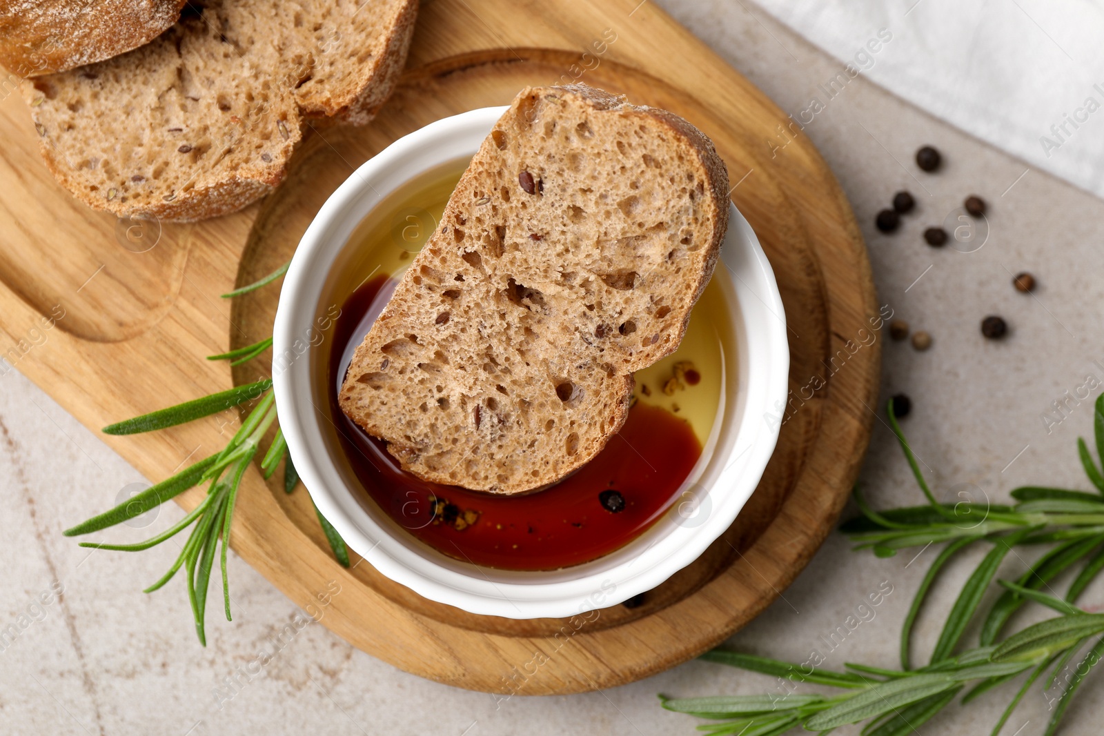 Photo of Bowl of organic balsamic vinegar with oil served with spices and bread slices on beige table, flat lay