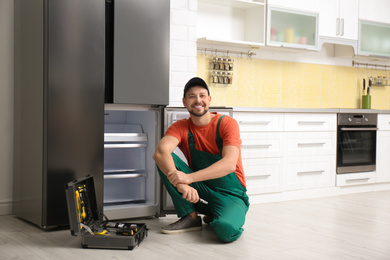 Photo of Male technician with pliers near refrigerator indoors