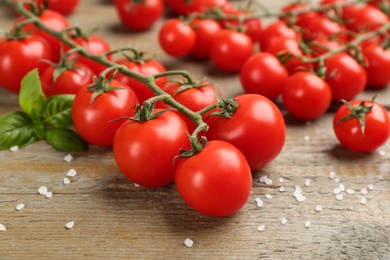 Photo of Fresh cherry tomatoes, sea salt and basil leaves on wooden table, closeup