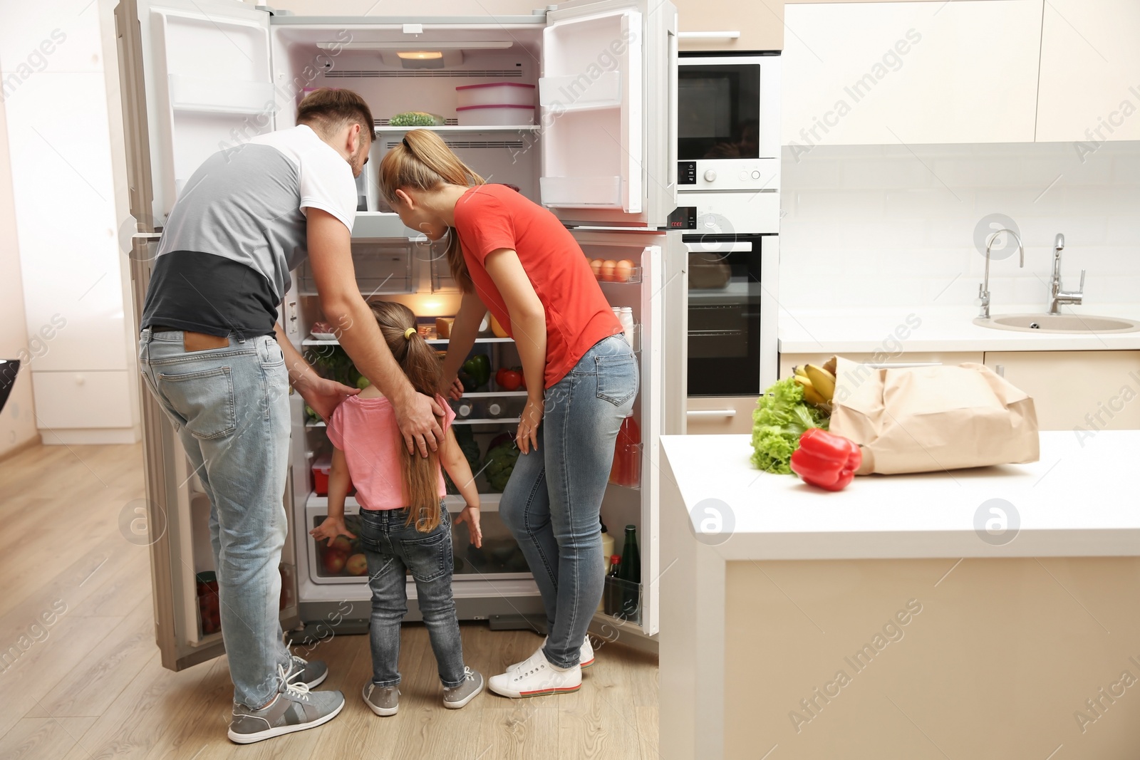 Photo of Young family choosing food in refrigerator at home