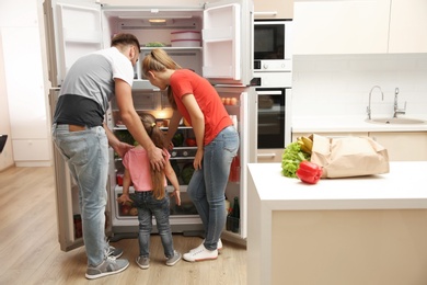 Young family choosing food in refrigerator at home