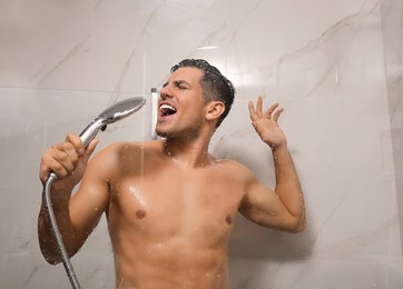 Photo of Handsome man singing while taking shower at home