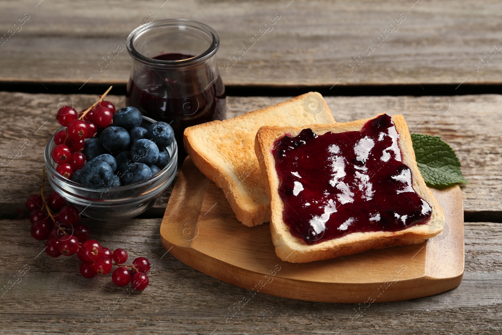 Photo of Delicious toasts served with jam and berries on wooden table