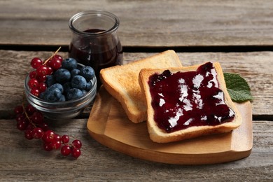 Delicious toasts served with jam and berries on wooden table